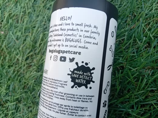 A black pet cologne spray bottle standing on grass